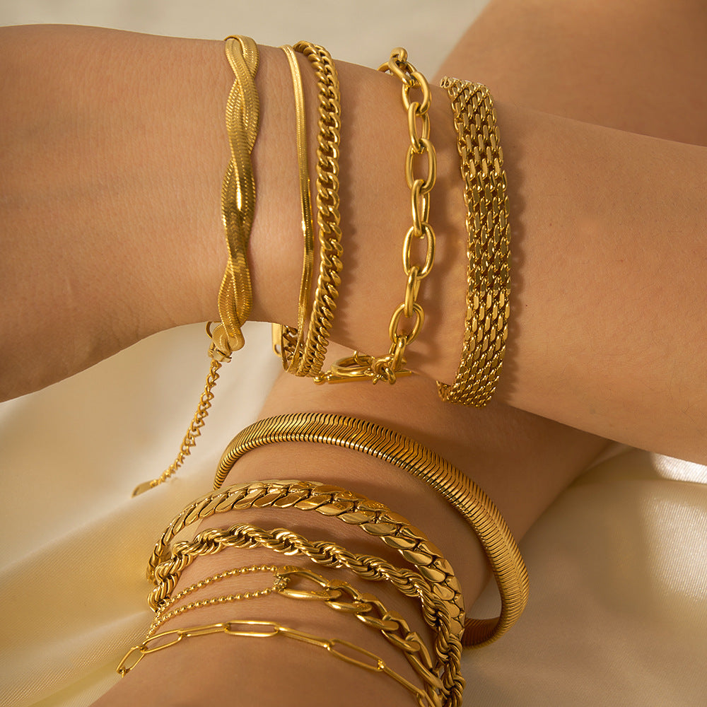 Gold bracelets on a wrist against a neutral background