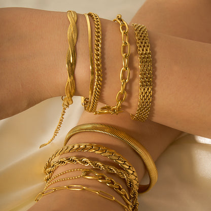 Gold bracelets on a wrist against a neutral background