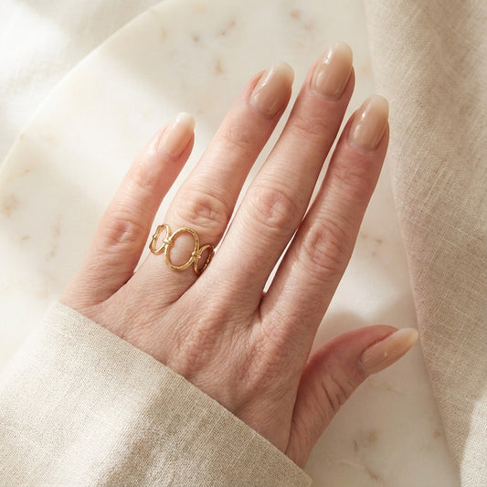 hand wearing a gold ring on beige background