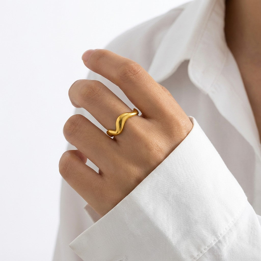 a woman in white shirt wearing a gold wavy ring