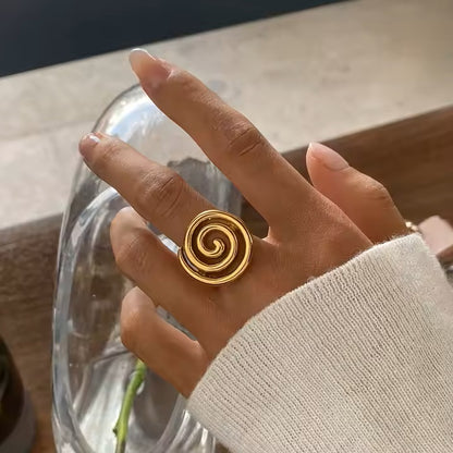 Gold spiral ring on a hand with a blurred background