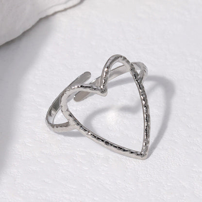 Silver heart-shaped ring on a white fabric background