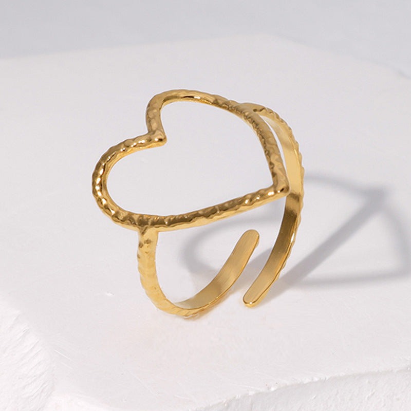 Gold open heart-shaped ring on a light gray background